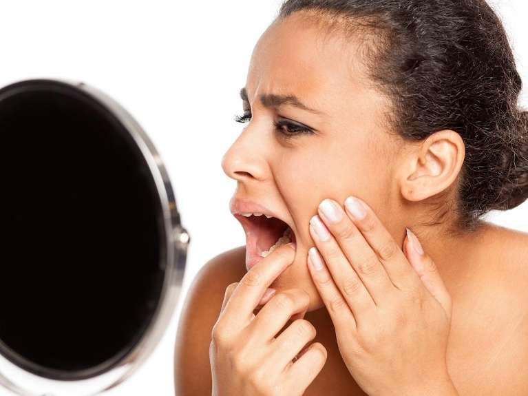 Worried woman checking gums in West Chester OH